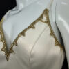 Close-up of the Gilded Venus bridal gown, highlighting intricate gold lace details and delicate beading on the bodice.