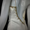 Back view of the Gilded Venus gown, displaying ornate gold embroidery and a dramatic, flowing skirt.