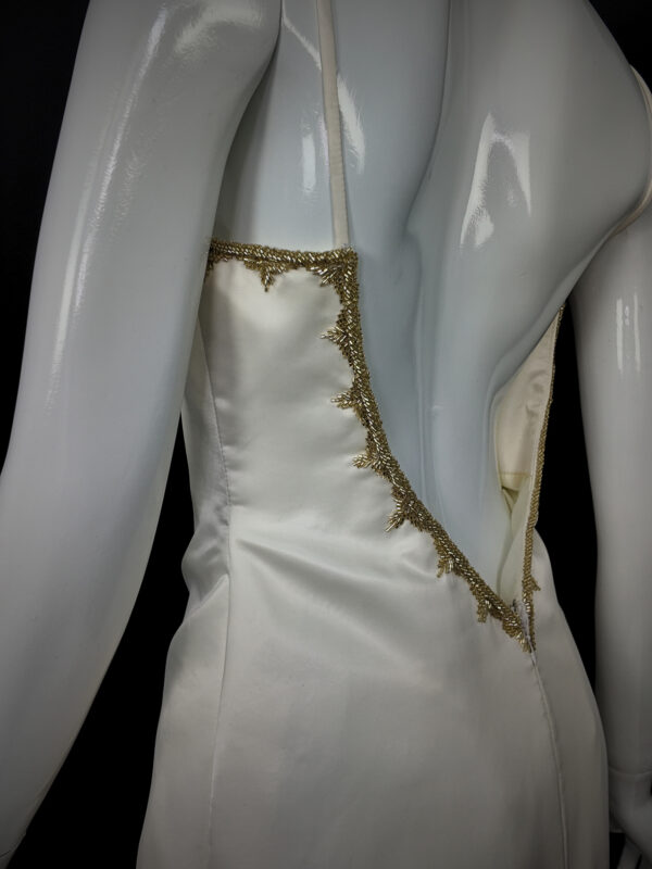Back view of the Gilded Venus gown, displaying ornate gold embroidery and a dramatic, flowing skirt.