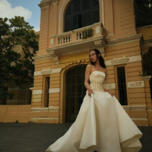 Bride wearing the Imperia A-line wedding dress, featuring an embroidered bodice and voluminous tulle skirt in a sunlit outdoor setting.